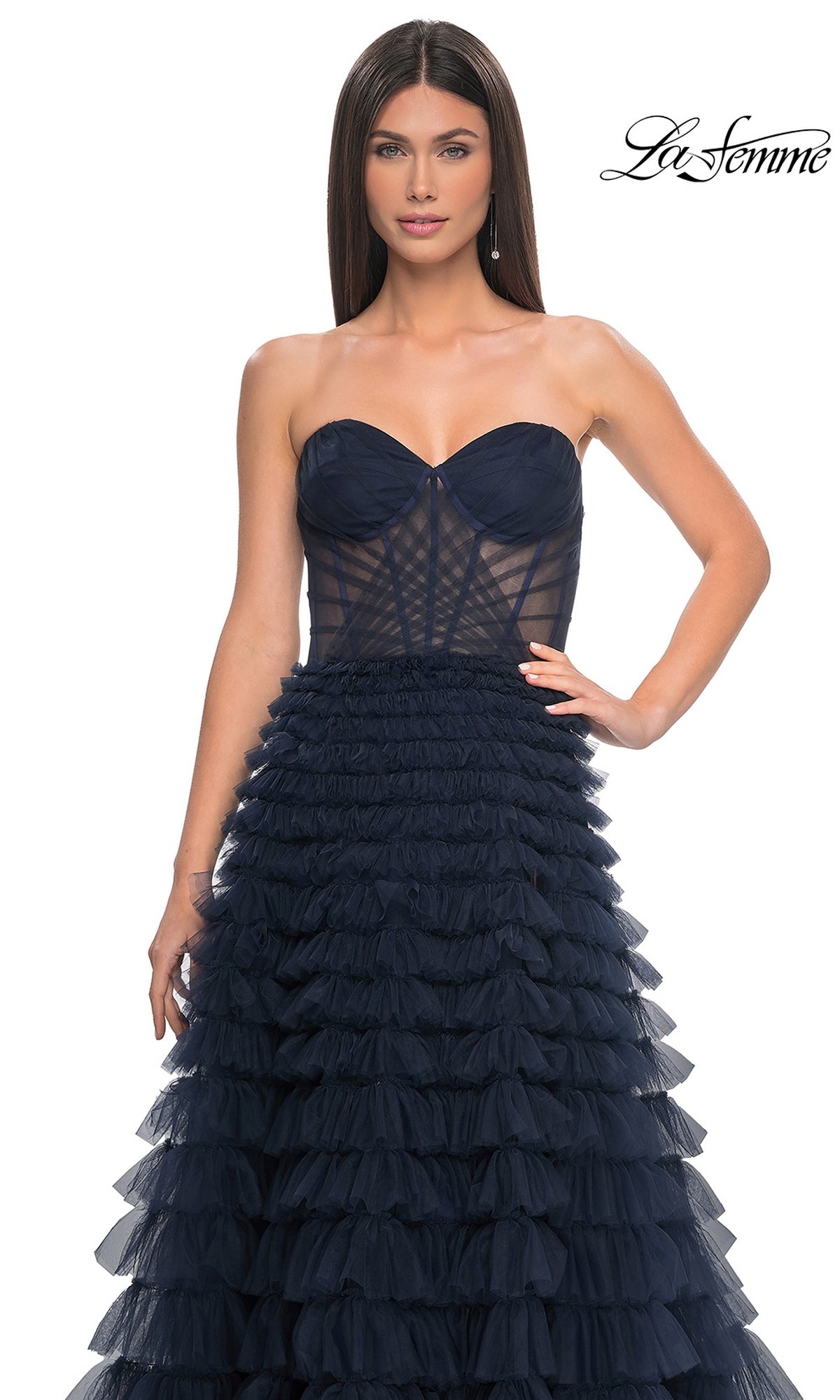 A woman wears the La Femme Strapless Long Ruffled Prom Dress 32283, a navy blue tulle gown with a strapless, fitted sheer bodice and ruffled A-line details. The La Femme logo appears in the top right corner.
